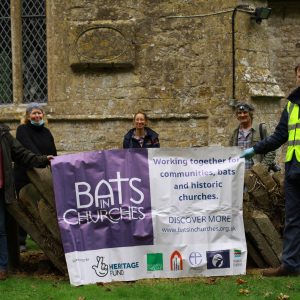 People standing with a Bats in Churches banner outside Radstone church