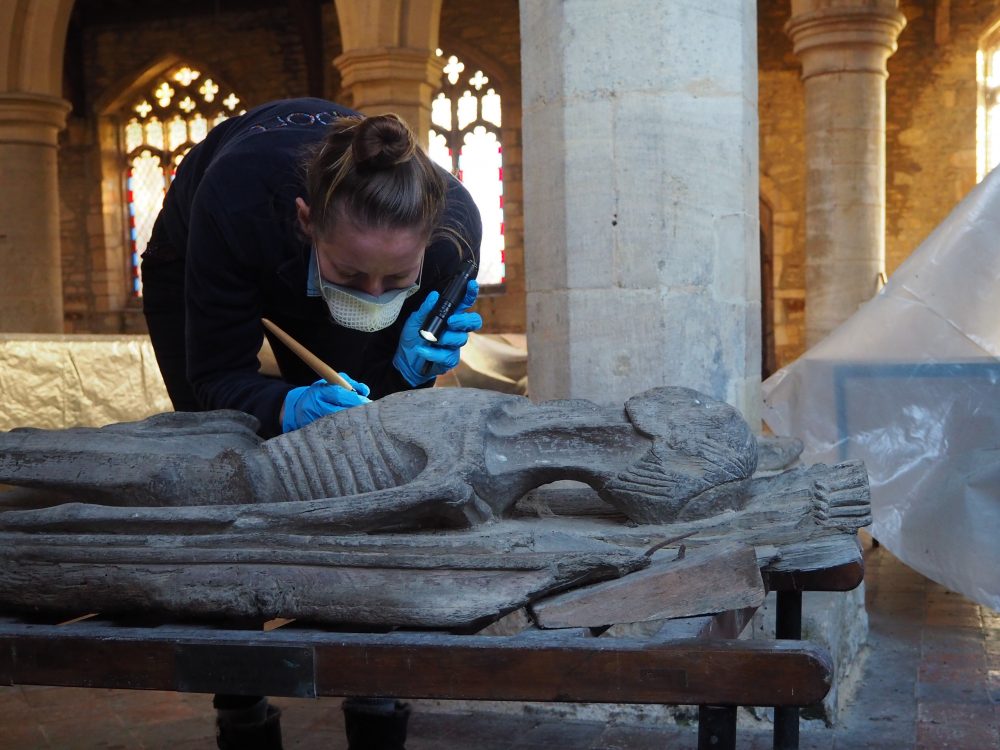 Rachel Arnold inspecting and cleaning the wooden cadaver in Keyston church