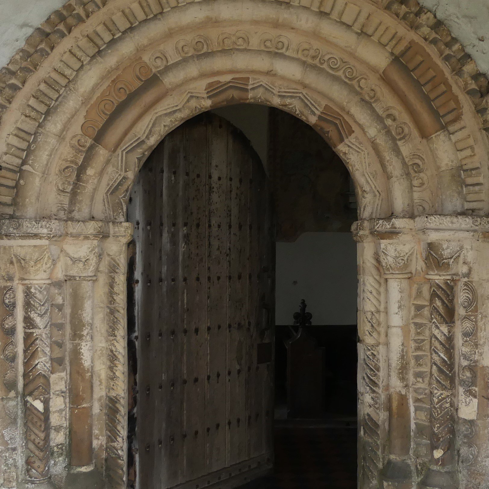 A stone doorway with a round arch. the door is surrounded by pillars and concentric arches each carved in regular geometric patterns