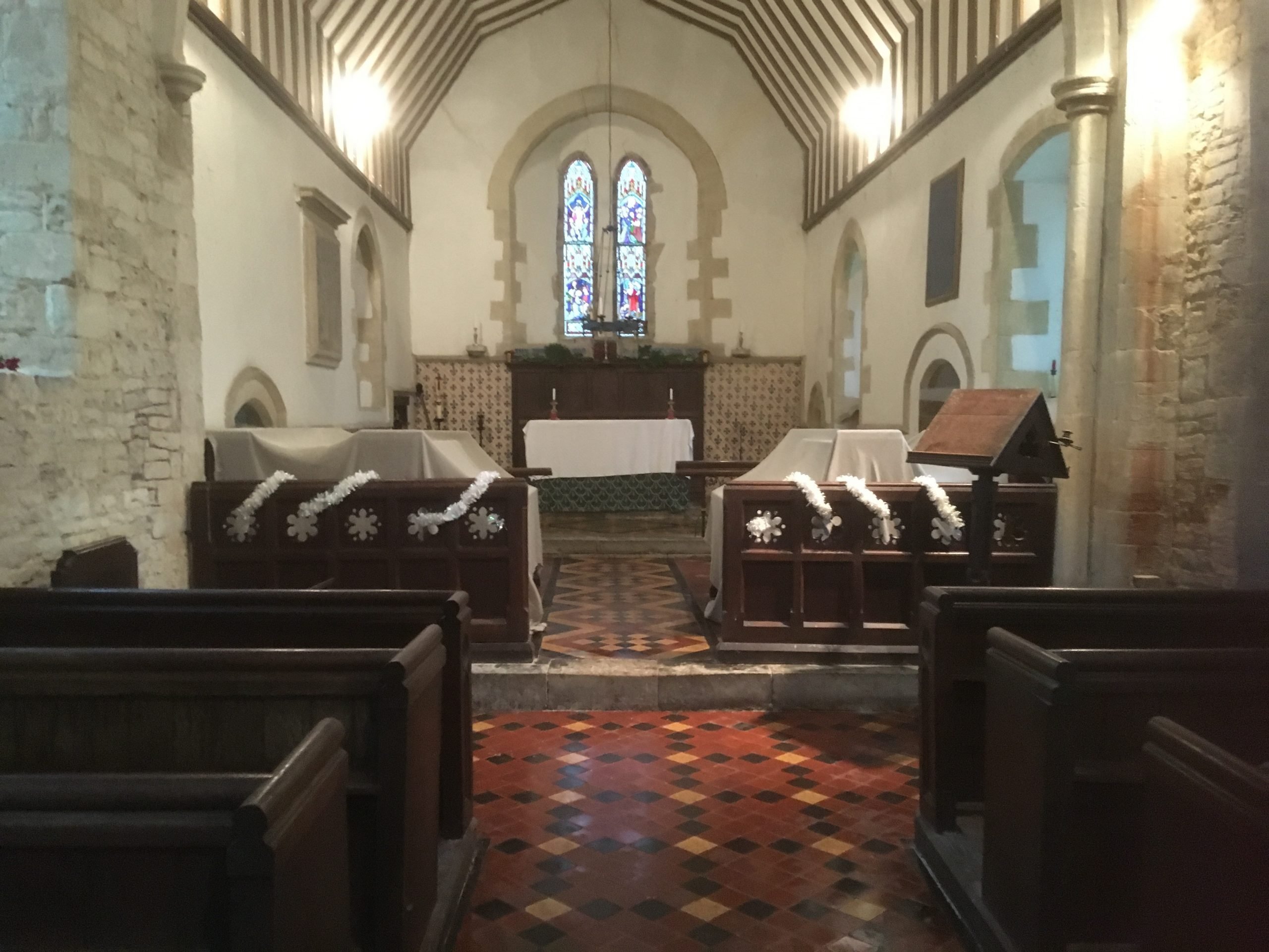 Interior of church ready for Christmas looking towards the chancel, with covers on choir stalls to protect from bat droppings