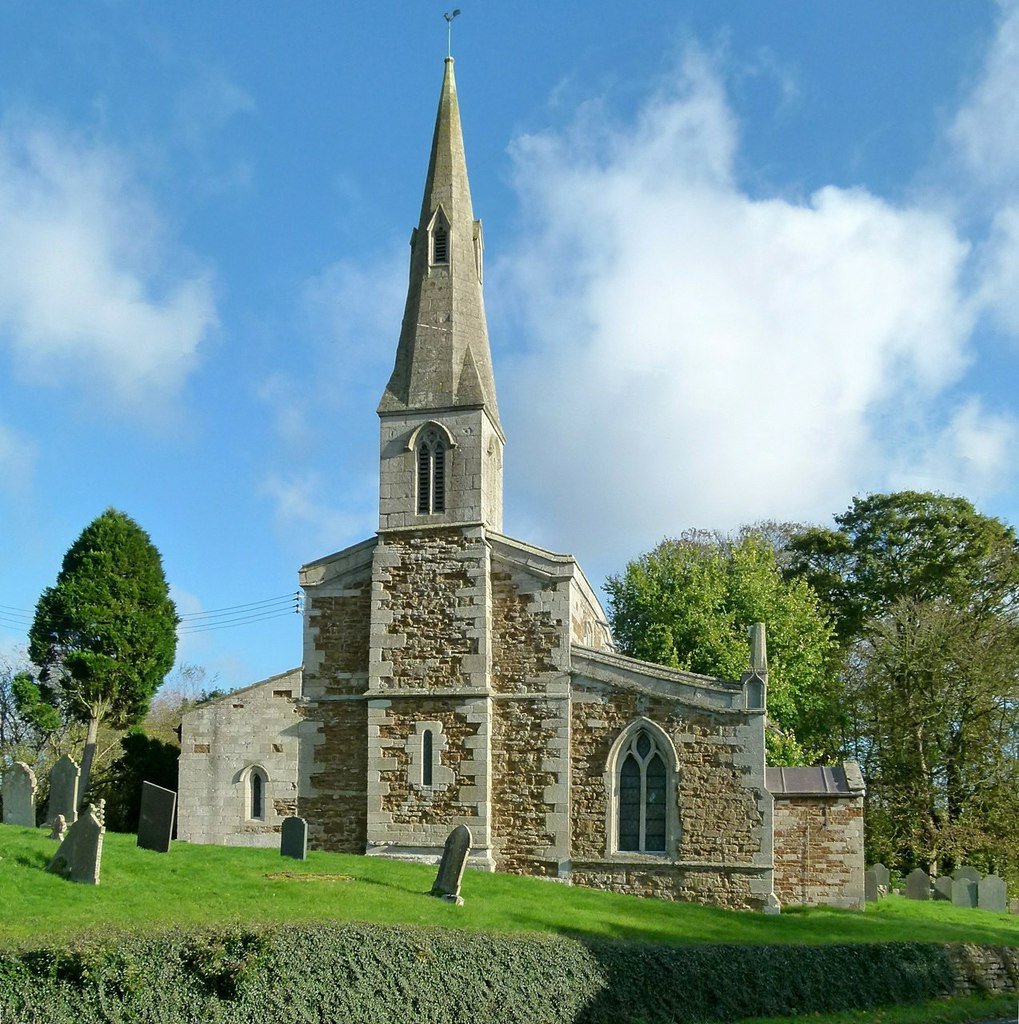 West end of stone church with delicate spire and Norman lancet window