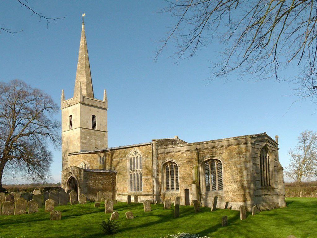 Stone church with tower and spire against a blue sky