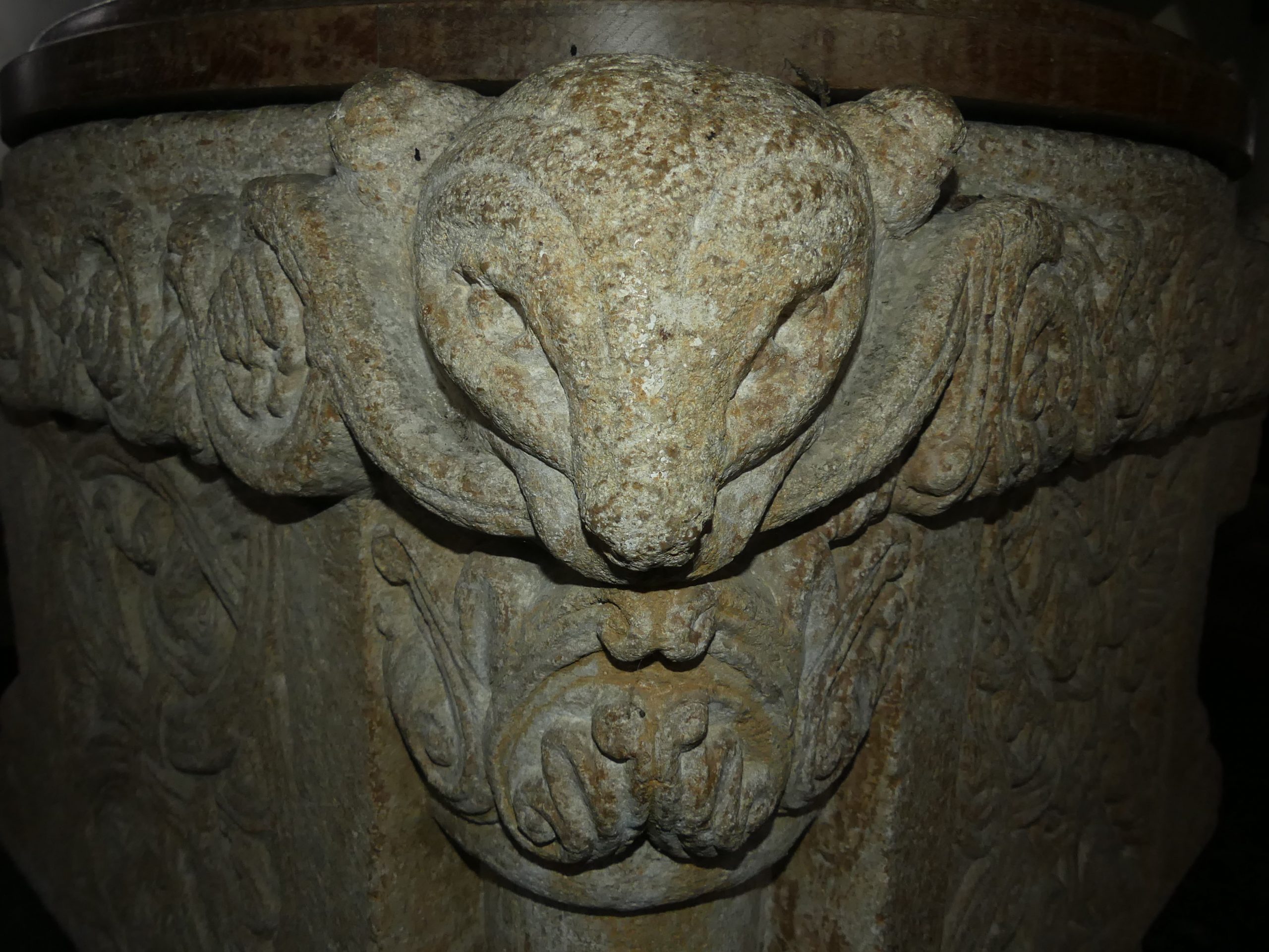 The corner of a square, Norman font carved with a stylised animals head looking directly at the camera