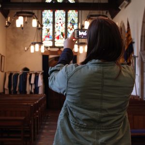 A young woman using a mobile phone to take a photo of the inside of a church