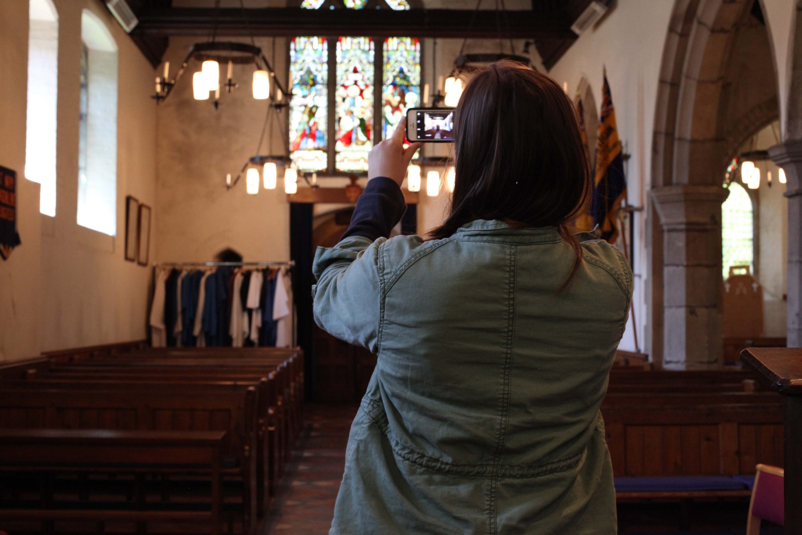 A young woman using a mobile phone to take a photo of the inside of a church