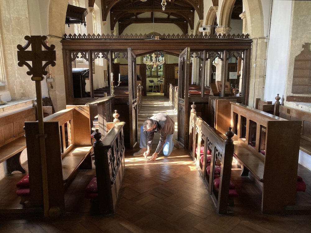 A volunteer collecting bat droppings from the floor of a church