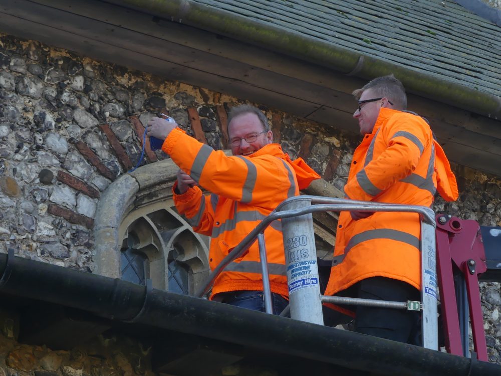 Two people in high visibility clothing working on the exterior of a church