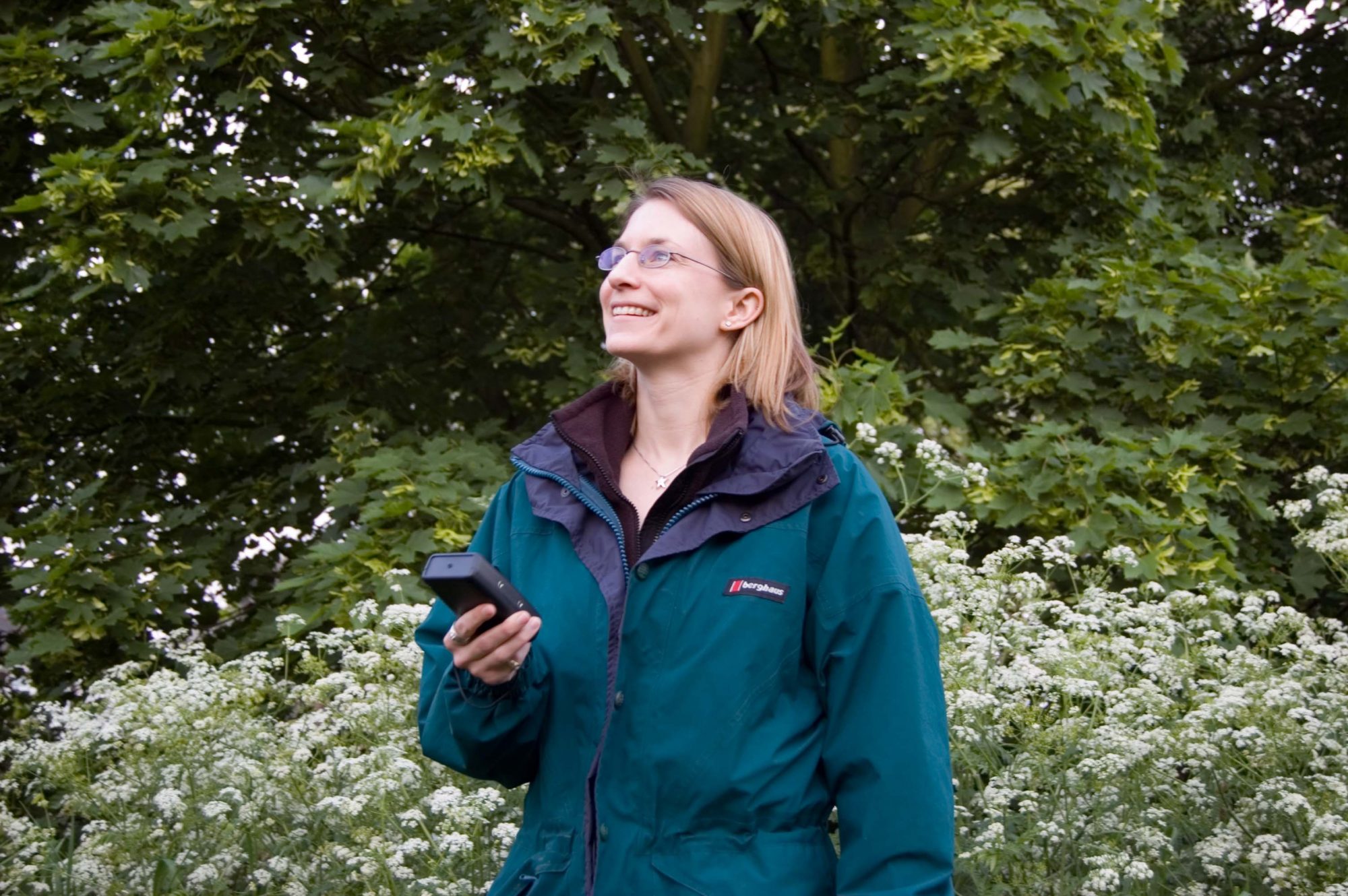 Image of a woman in outdoor clothing holding a bat detector