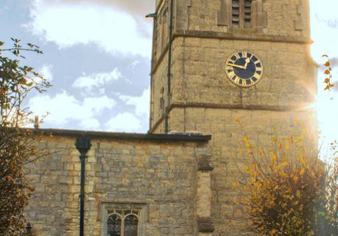 Church bell tower with clock and sunbeams