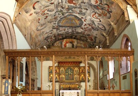 Painted ceiling of church chancel with rood screen and triptych behind altar