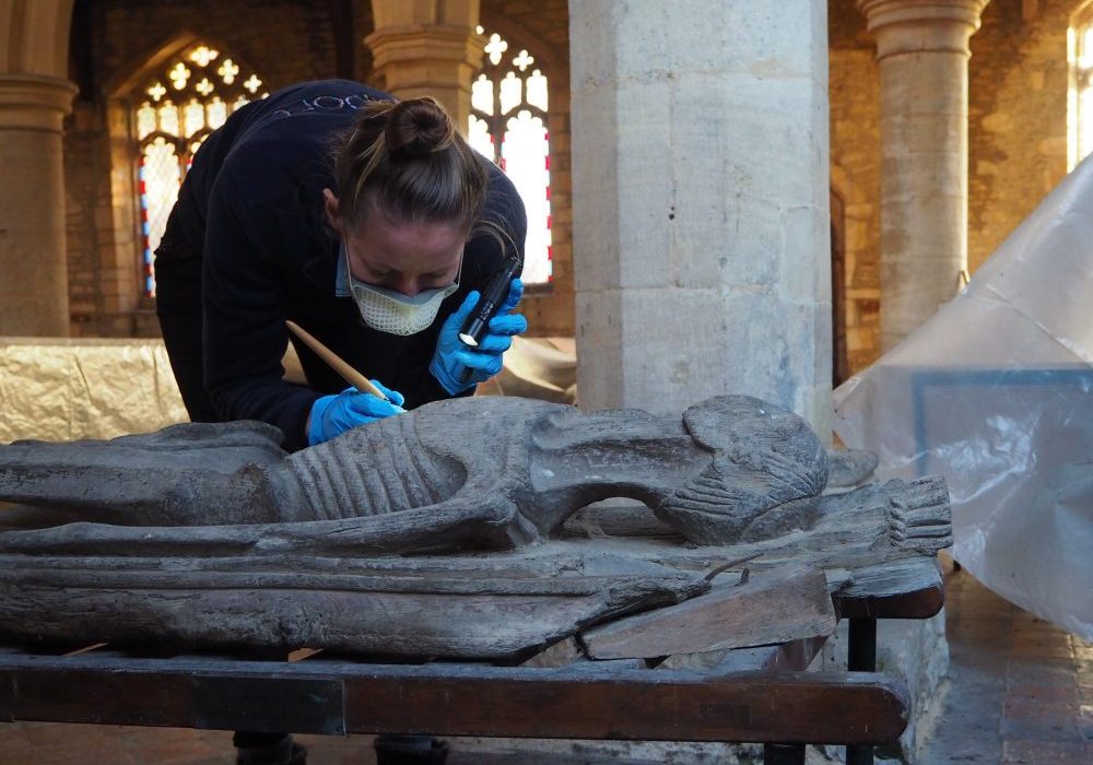Rachel Arnold inspecting and cleaning the wooden cadaver in Keyston church