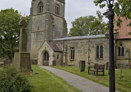 Exterior of stone church from south with iron lampost beside path leading to south porch