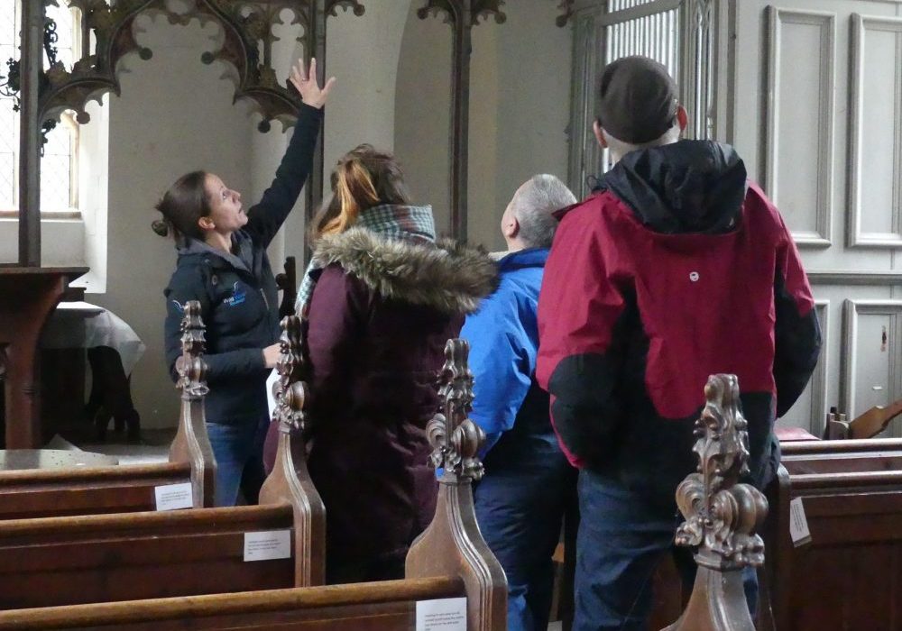 A young, female ecologist pointing out bat roosting space in the church at Dunston in Norfolk.