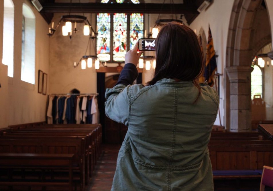 A young woman using a mobile phone to take a photo of the inside of a church